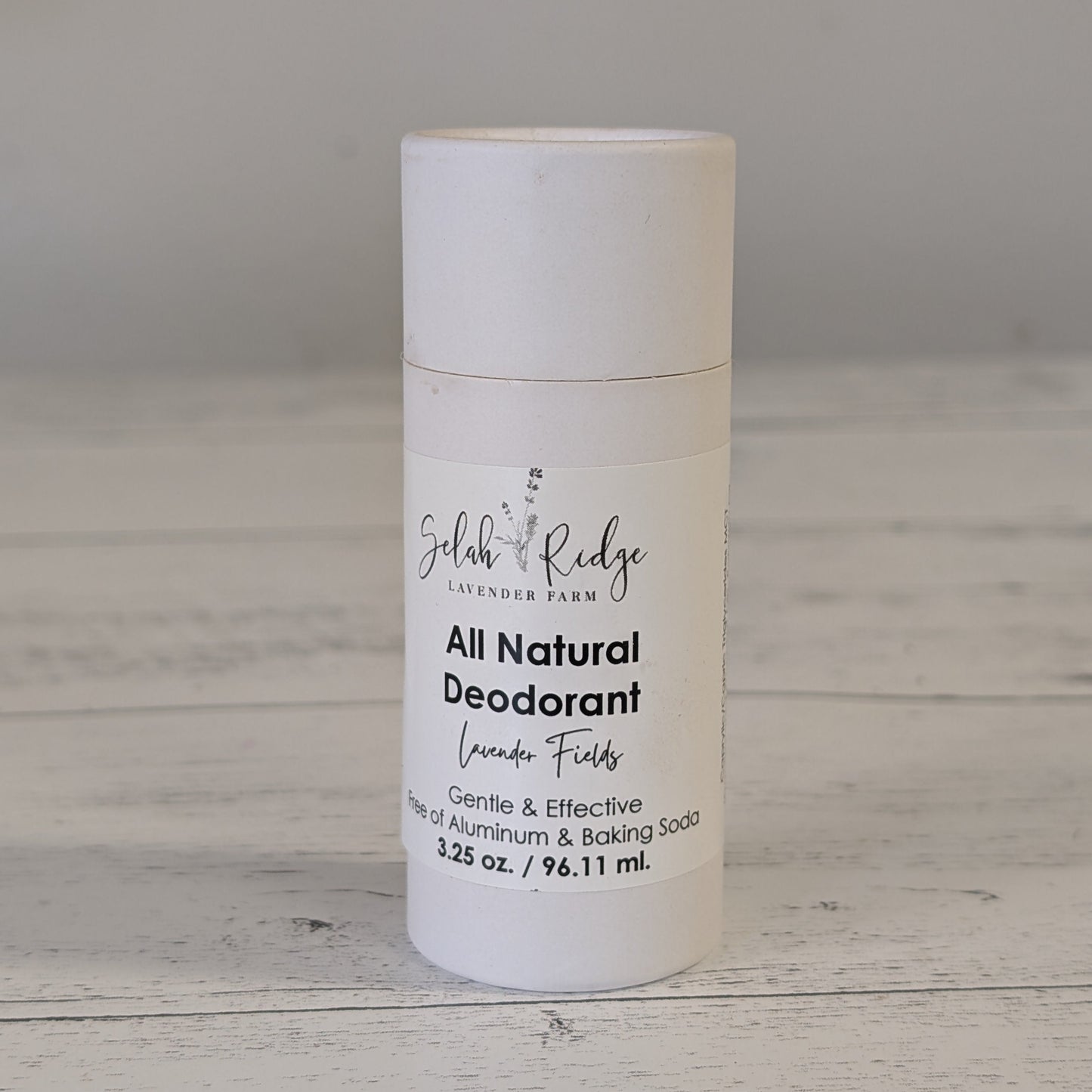 All natural deodorant bottle on a wooden surface with a gray background