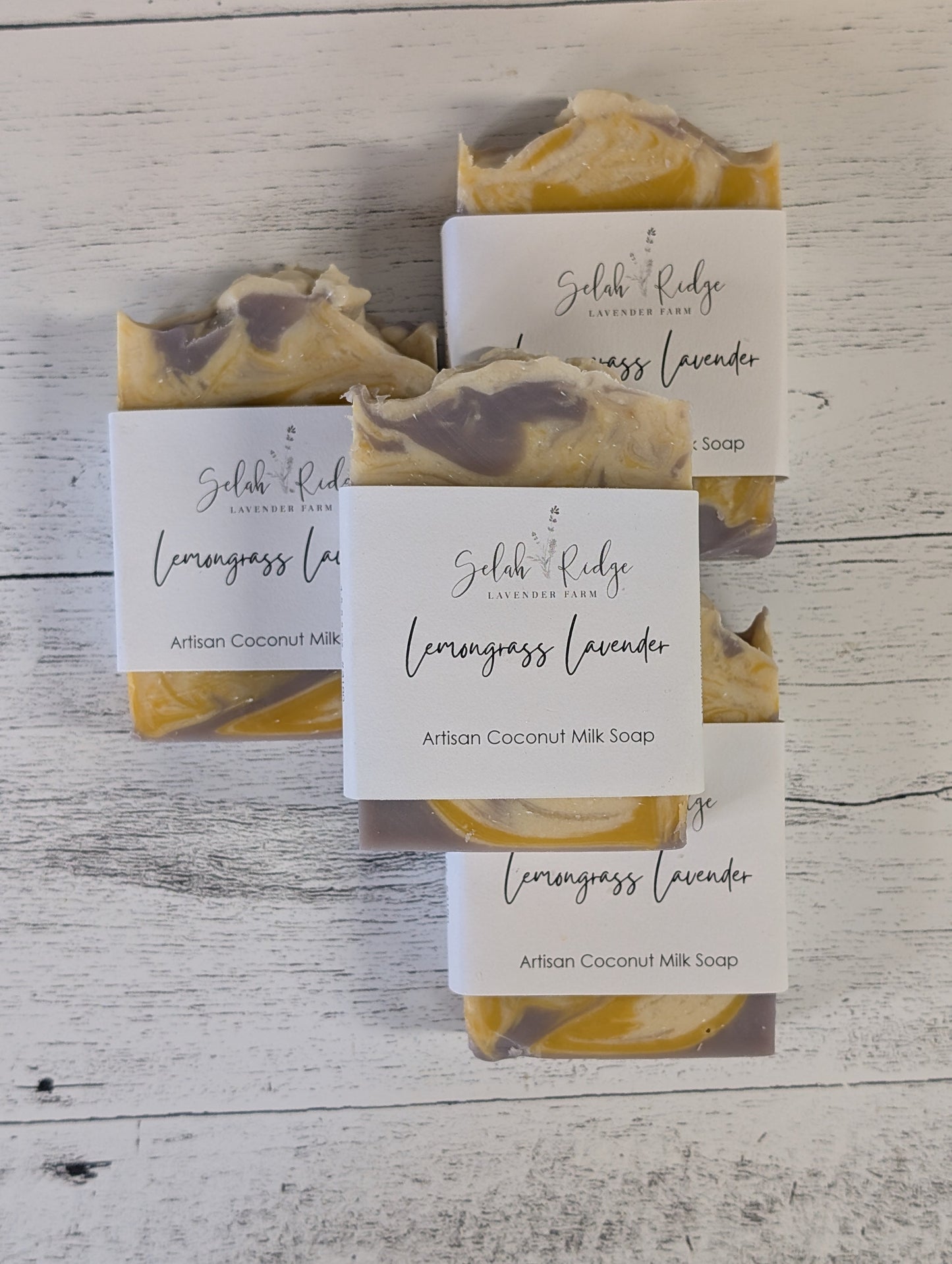 Three bars of soap with visible marbled design on a white wooden surface, each accompanied by a small card.