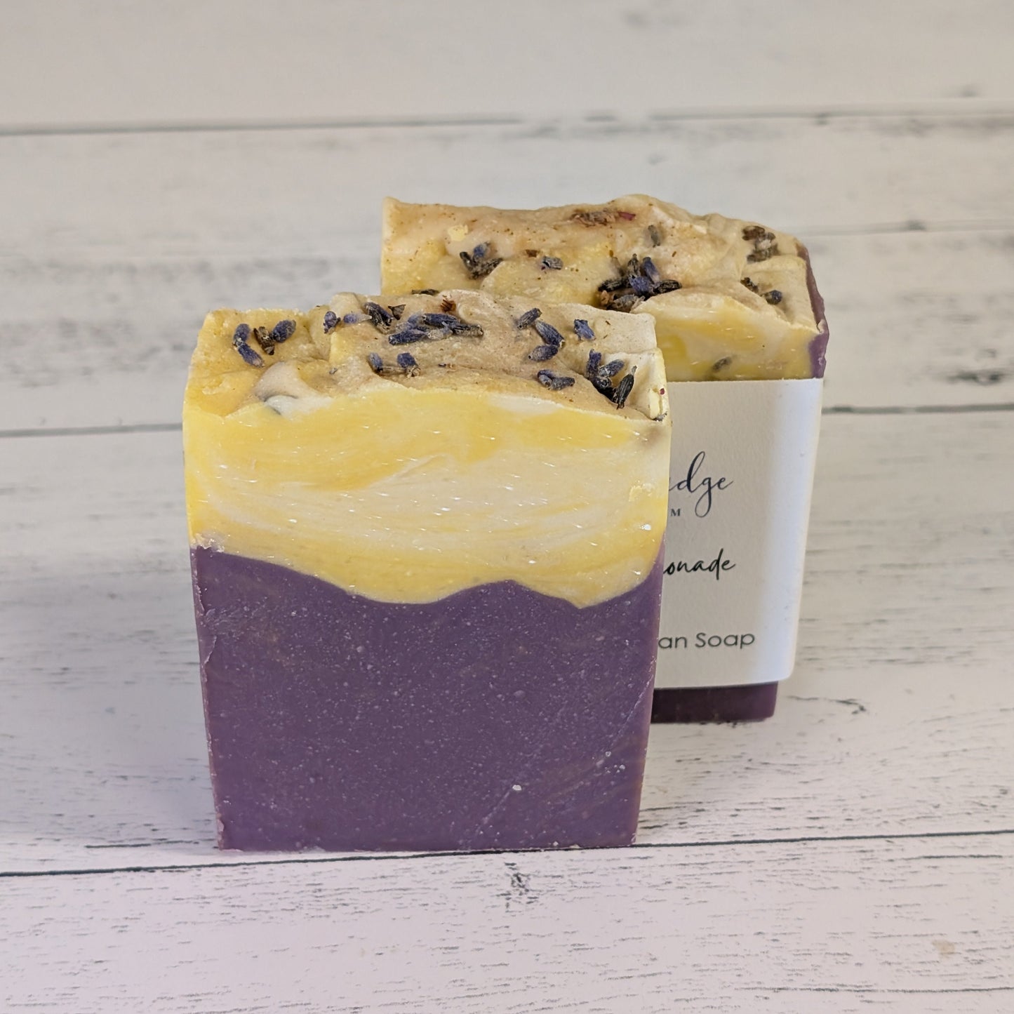 Two layered soap bar with purple and yellow on a wooden surface