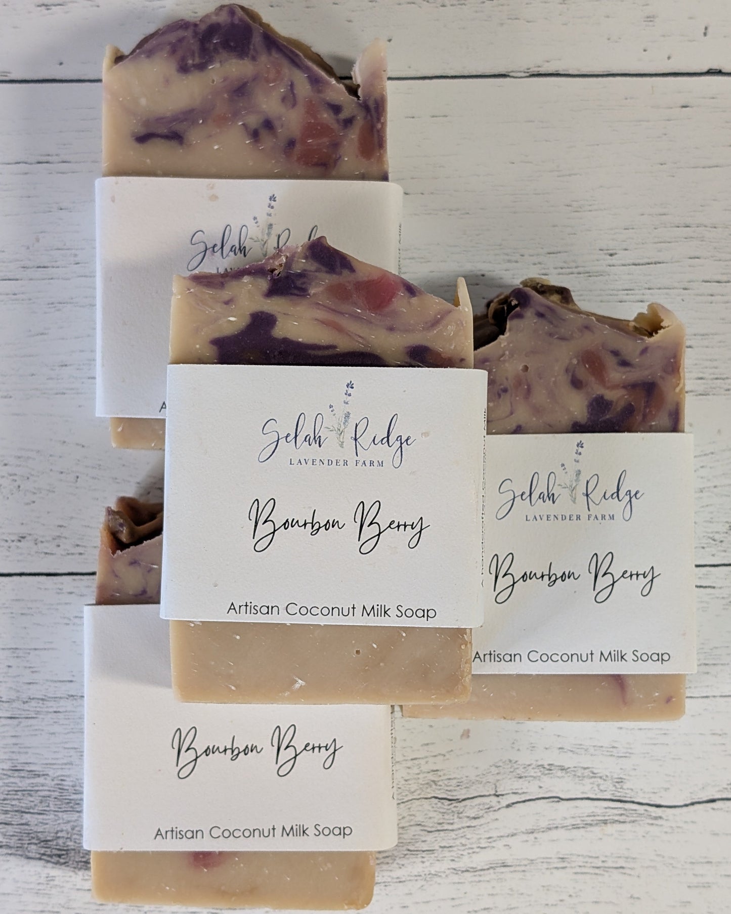 Stack of Bourbon Berry artisan coconut milk soap bars with visible brand name on a wooden surface