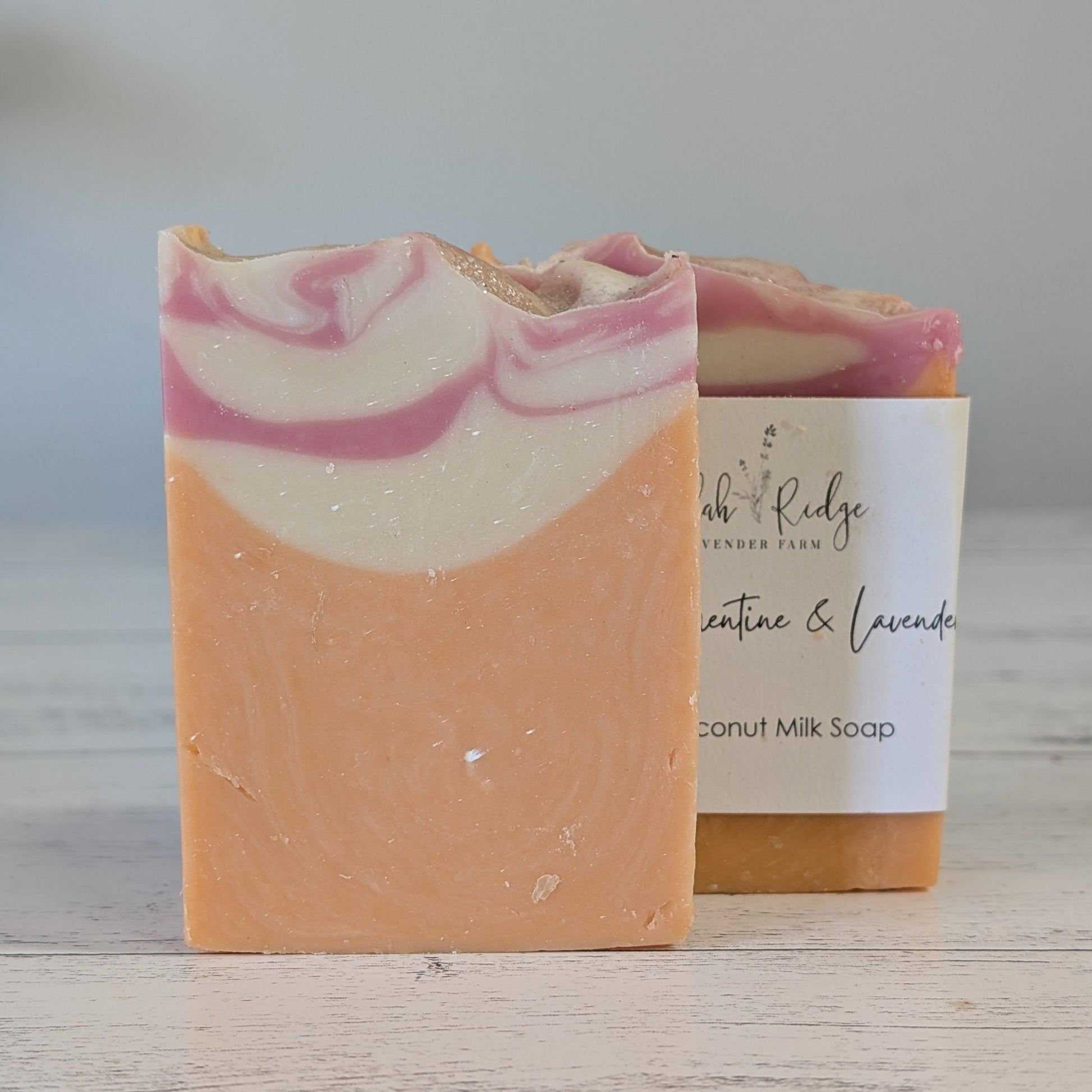 Bar of soap with pink and white swirls next to a label on a wooden surface